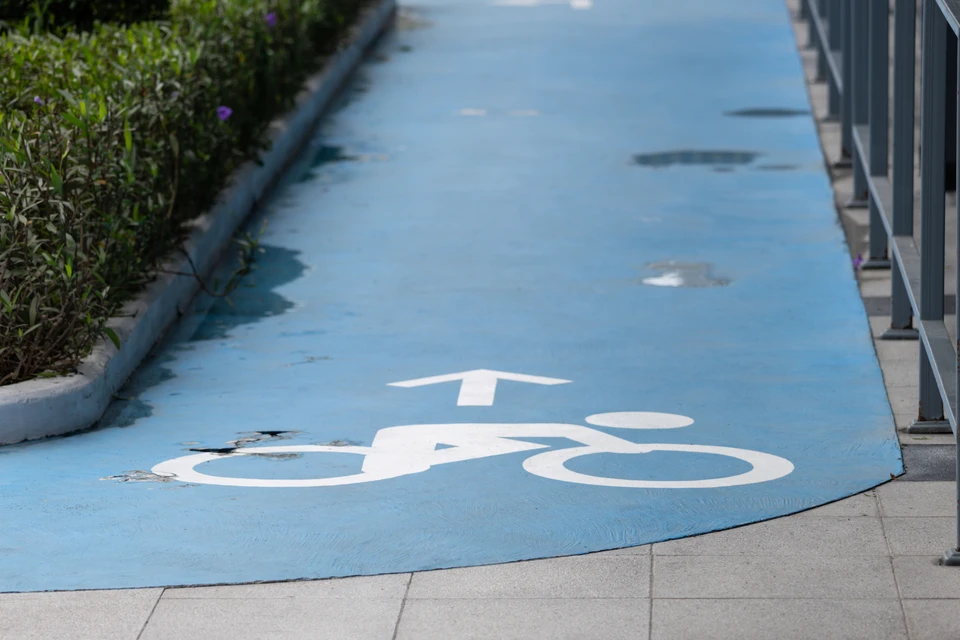 Un agent de nettoyage professionnel à vélo, photographié en mouvement ou en position de travail, portant un équipement de nettoyage adapté au transport à vélo (sac ou porte-outils fixé au vélo), dans un environnement urbain de Nantes avec immeubles résidentiels ou commerciaux en arrière-plan. L'image doit transmettre dynamisme, éco-responsabilité et accessibilité du service de nettoyage en milieu urbain.