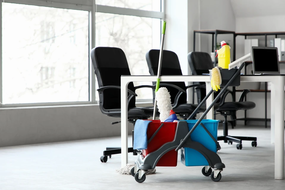 Agent de nettoyage professionnel à vélo équipé de matériel compact et d'aspirateur sans fil, devant ou près d'un bâtiment professionnel ou d'une copropriété à Nantes, portant un uniforme ou tenue professionnelle, le vélo équipé de sacoches ou porte-matériel adapté, illustrant une démarche écologique et efficace de nettoyage urbain.